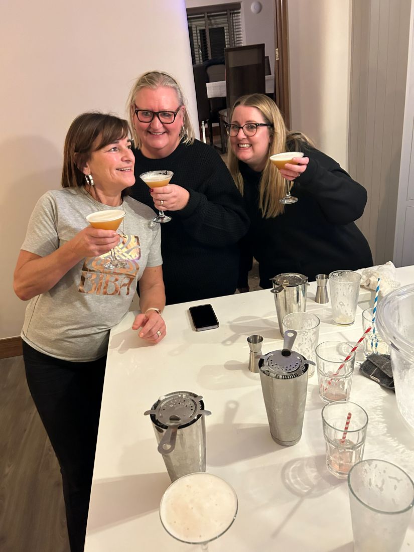 Three guests clinking espresso martinis in a kitchen