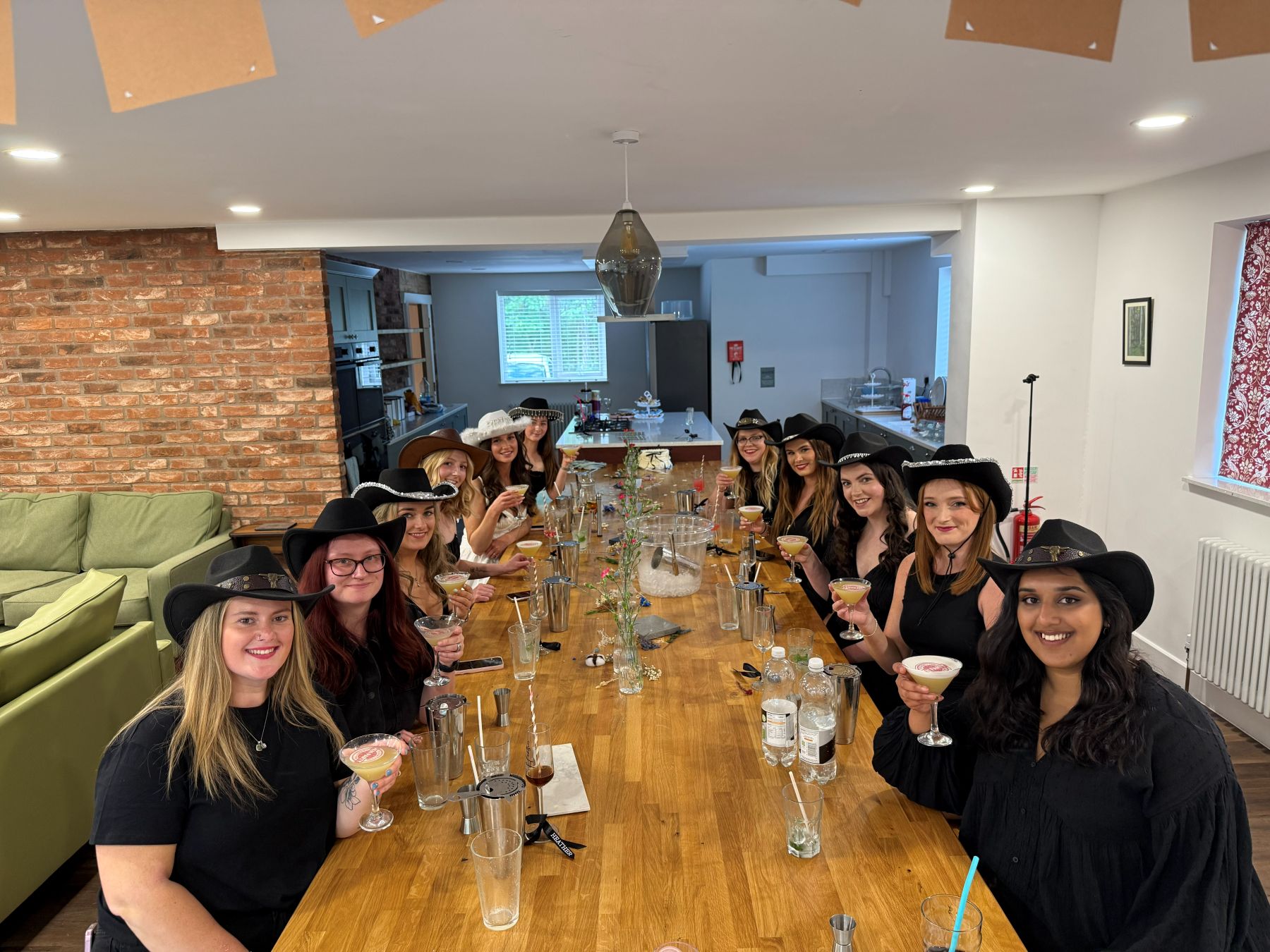 A hen party in cowboy hats raising their pornstar martinis around a long table