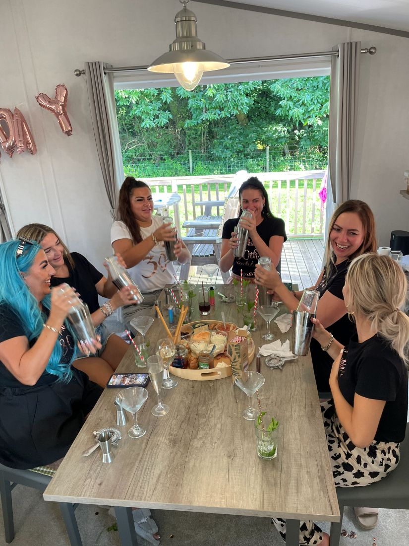Friends laughing around a table of shakers and finished cocktails