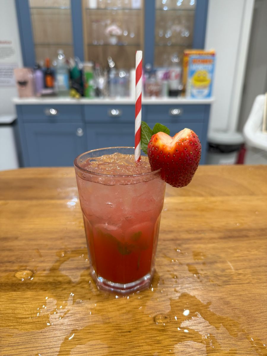 A tall strawberry cocktail with a fresh strawberry on the rim