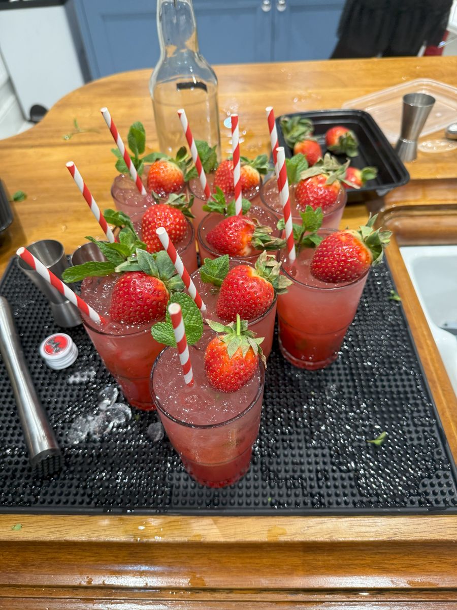 A row of strawberry mojitos garnished with fresh strawberries and paper straws