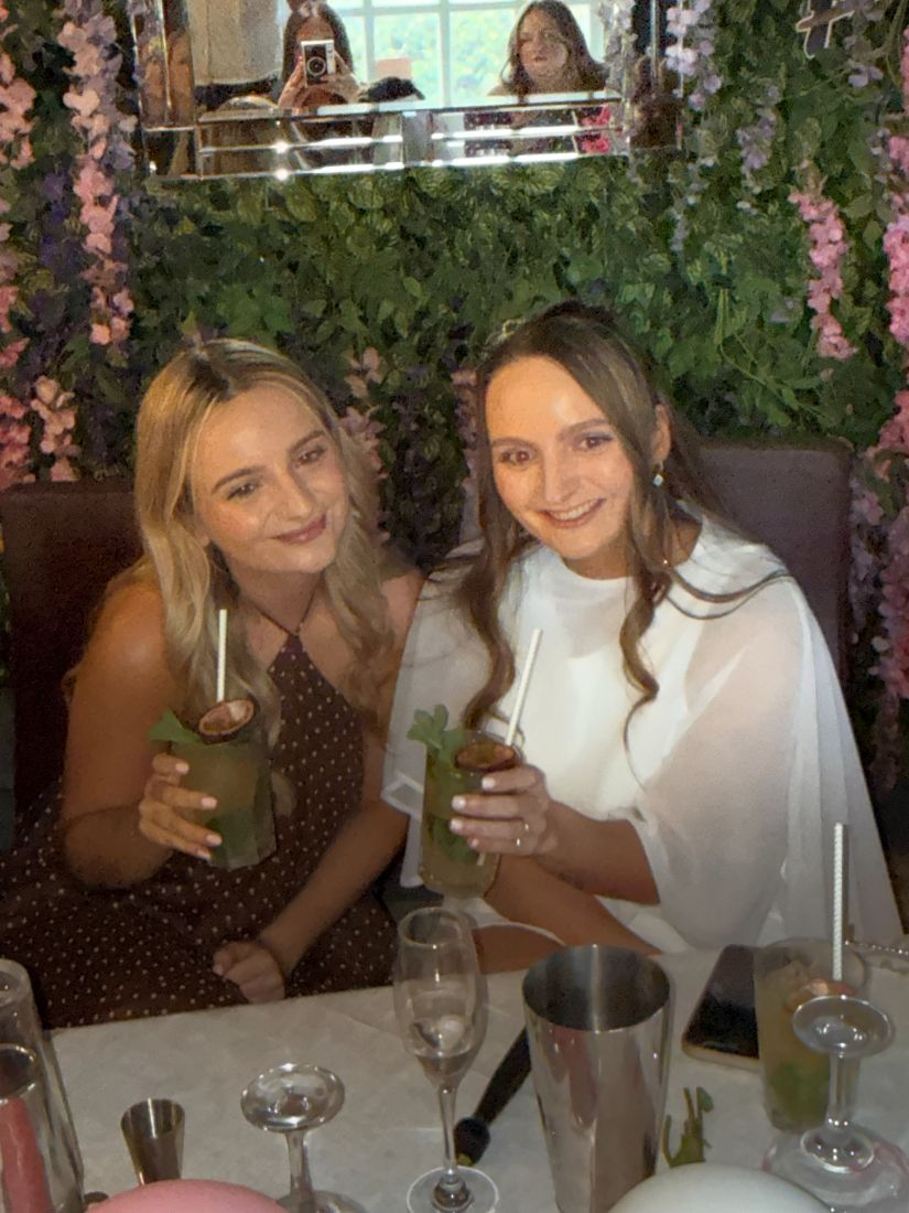 Two friends with fresh mojitos in front of a floral wall